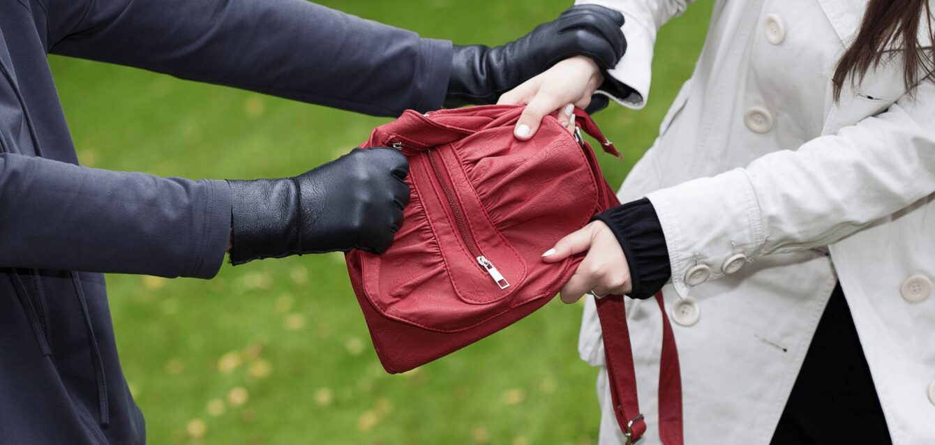 Hombre robando cartera roja a mujer