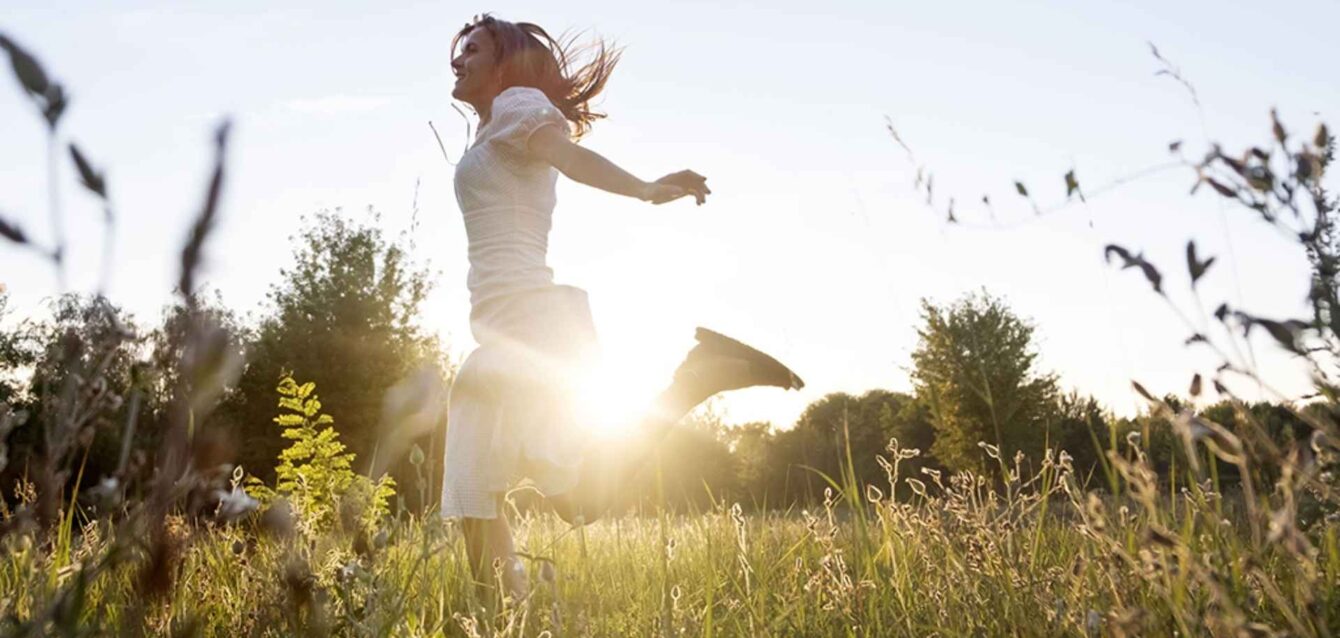 Mujer feliz corriendo en un campo